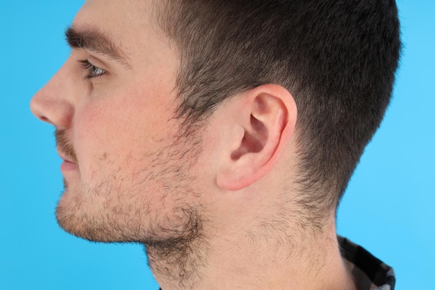 Photo vue de côté de la tête d'un jeune homme sur fond bleu