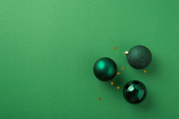 Photo vue de dessus de boules de sapin de noël vertes et de paillettes dorées sur fond vert isolé avec espace vide