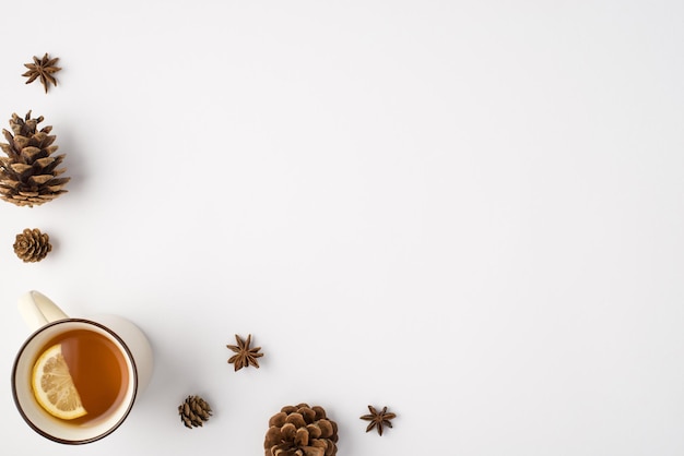 Photo vue de dessus de la composition hivernale des pommes de pin anis et tasse de thé au citron sur fond blanc isolé avec espace pour copie