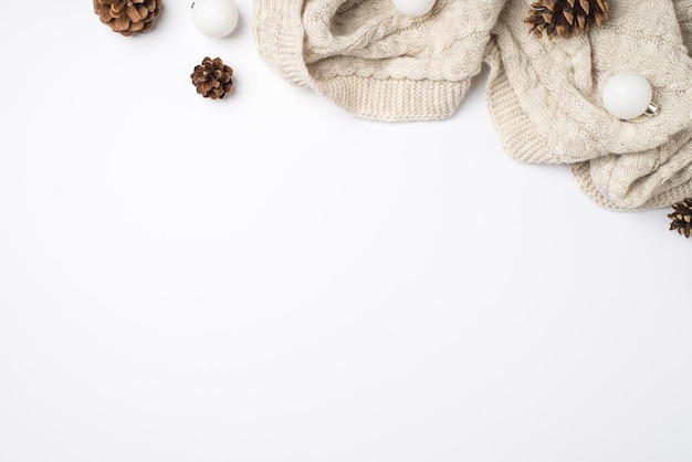 Photo vue de dessus de cônes de pin écharpe tricotés confortables et de boules de sapin de noël blanches sur fond blanc isolé avec espace vide