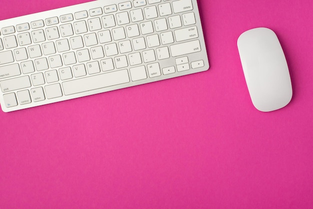 Photo vue de dessus du bureau avec clavier et souris blancs sur fond rose isolé avec espace de copie