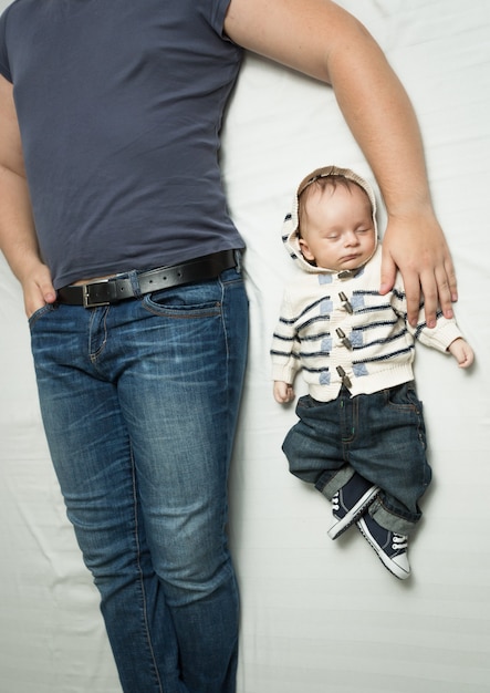 Photo vue de dessus du jeune père élégant et du petit garçon en jeans allongé sur le lit