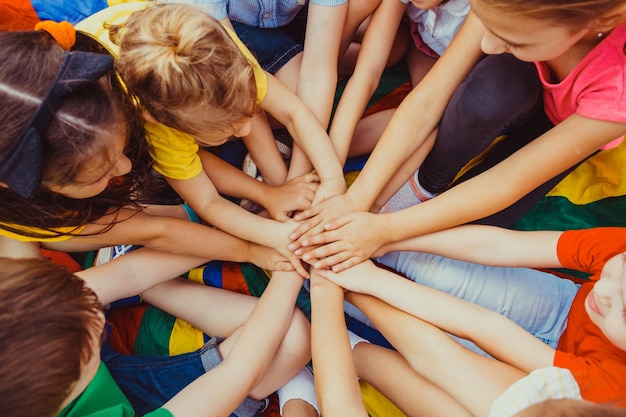 Photo vue de dessus d'une équipe d'enfants concluant un accord, mettant leurs mains ensemble. Enfants agitant leurs mains, bonne coopération