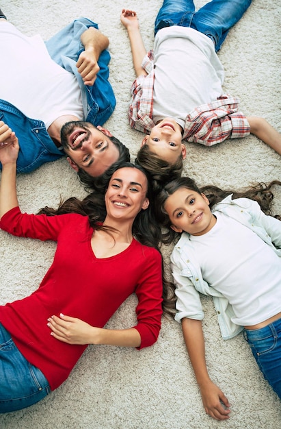 Photo vue de dessus d'une jeune famille heureuse allongée sur le sol, s'amuser et sourire