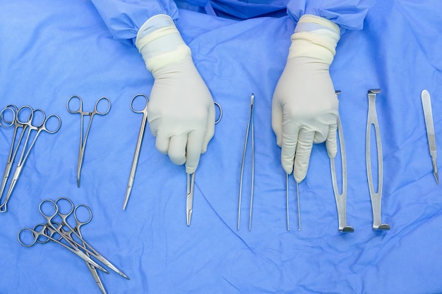 Photo vue de dessus La main du chirurgien et les instruments chirurgicaux dans la salle d'opération préparent les instruments chirurgicaux qui sont stériles pour le médecin du cabinet. Concept : médical