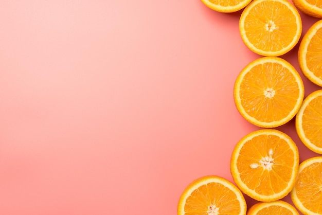 Photo vue de dessus d'oranges coupées à droite sur fond rose pastel isolé avec espace pour copie à gauche