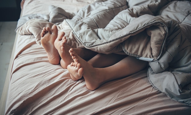 Photo vue de dessus des pieds d'un couple au lit dormir ensemble