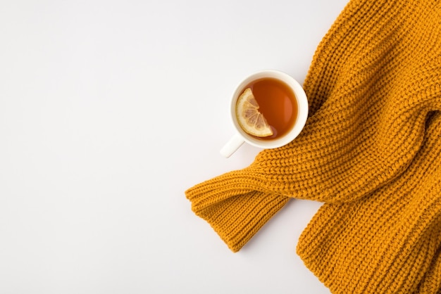 Photo vue de dessus d'un pull orange et d'une tasse de thé au citron sur fond blanc isolé avec espace pour copie