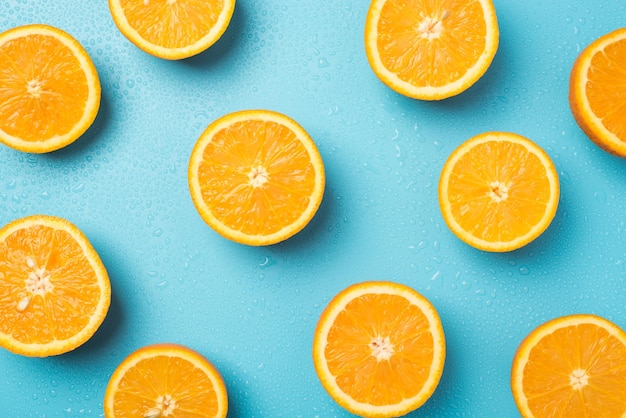 Photo vue de dessus de tranches d'orange juteuse et de gouttes d'eau sur fond bleu clair isolé