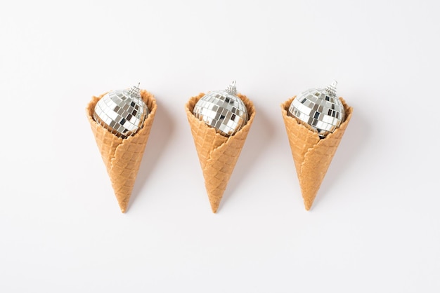 Photo vue de dessus de trois cônes de crème glacée avec des boules disco d'arbre de noël sur fond blanc isolé