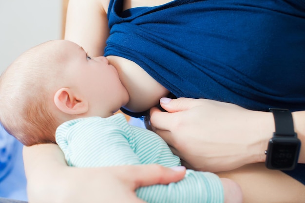 Photo vue latérale d'un adorable petit garçon qui suce les seins à la main de sa mère. Verrouillage approprié pour un allaitement confortable