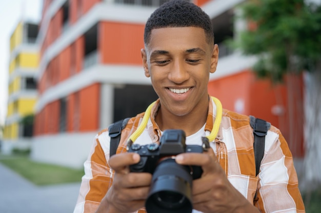 Un photographe afro-américain sélectionne des photos dans la rue Happy tourist holding digital camera