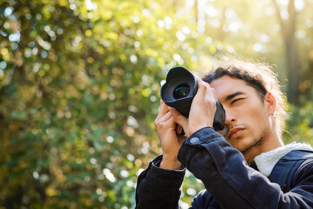 Photographe avec appareil photo moderne dans un parc