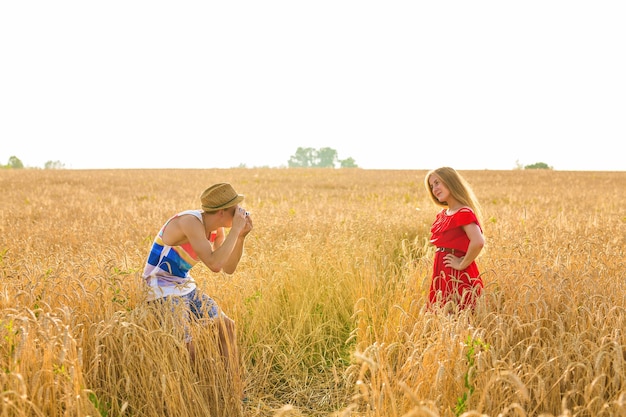 Photographe avec appareil photo prenant une photo d'une belle jeune femme sur le terrain.