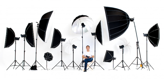 Un photographe assis sur la chaise du réalisateur avec des éclairages de studio éclairés
