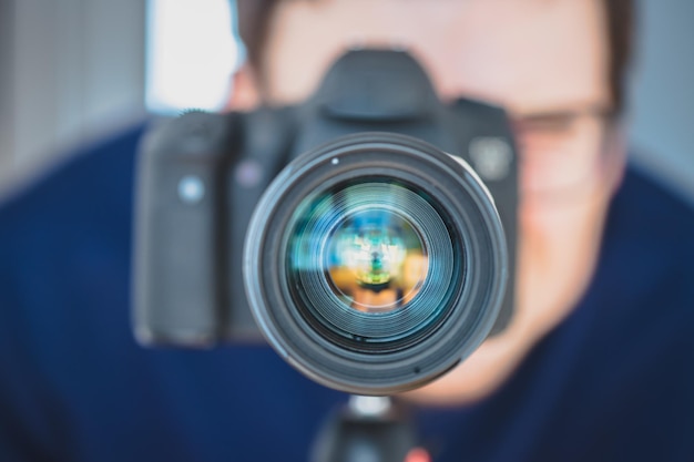 Photographe au travail L'homme se tient derrière un appareil photo professionnel sur un trépied pour prendre des photos