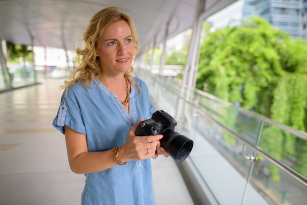 Photographe de belle femme touriste blonde à l'aide de l'appareil photo à l'extérieur