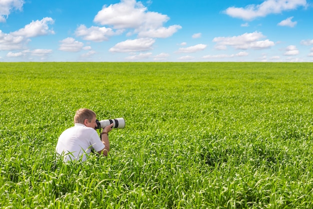 Le photographe sur un champ vert tire un paysage