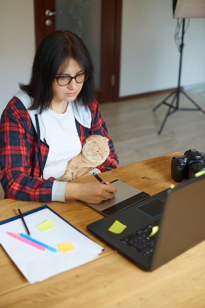 Photographe créative avec un chat mignon à l'aide d'une tablette de dessin graphique et d'un stylet