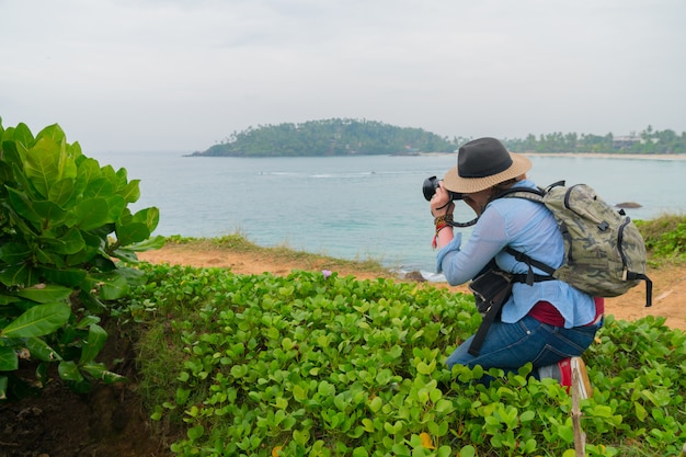 Le photographe dans un chapeau et avec un sac à dos prend une photo.