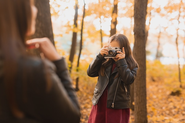 Photographe enfant fille prend des photos d'une mère dans le parc en automne. Loisirs, art photo et concept de loisirs.