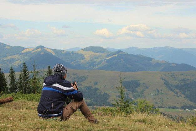 Photo le photographe est assis et regarde le paysage de la montagne.