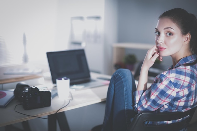 Photographe féminin assis sur le bureau avec un ordinateur portable