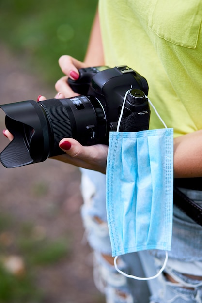 Photographe femme avec un appareil photo à la main en plein air avec masque de protection