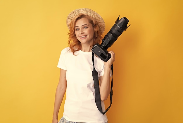 Photographe femme rousse joyeuse avec appareil photo en chapeau de paille faisant caméraman photo