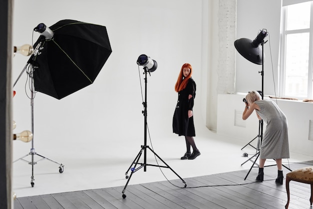 Photographe de fille photographiant le mannequin en couleur noire sur fond blanc en Studio