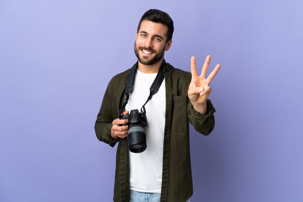 Photographe homme sur mur violet isolé heureux et en comptant trois avec les doigts