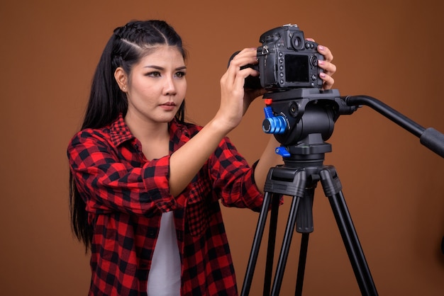 Photographe jeune femme asiatique réglage de la caméra sur trépied