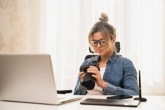 Photographe jeune et heureuse avec un appareil photo sans miroir sur le lieu de travail