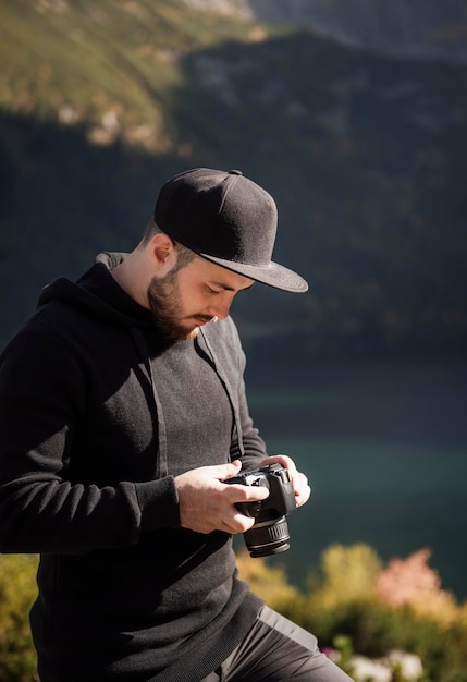 Photographe de jeune homme prenant des photos avec un appareil photo numérique dans une montagne