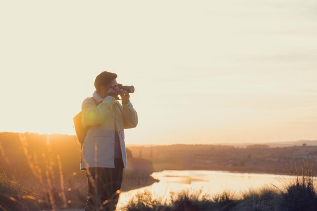 Un photographe latin avec un appareil photo prend des photos dans un lagon au coucher du soleil