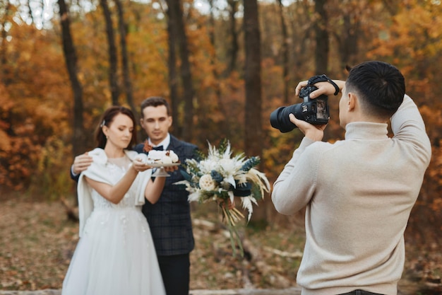 Photo photographe de mariage professionnel prenant des photos de la mariée et du marié dans la nature en automne