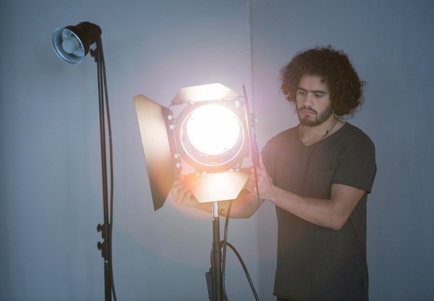 Photo photographe masculin ajustant le projecteur