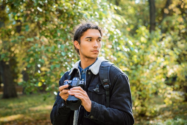 Photographe masculin avec caméra moderne prenant des paysages dans la forêt d'automne