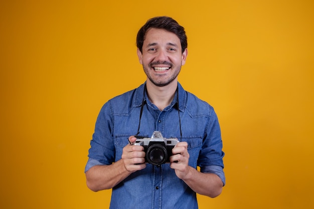 Photographe mignon sur fond jaune. homme avec un appareil photo