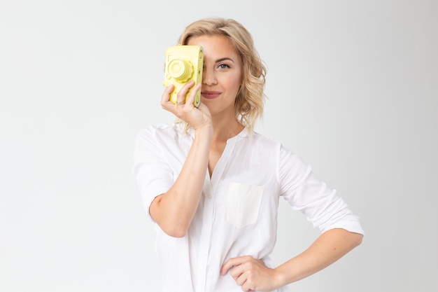 Photographe, passe-temps et concept de loisirs - jeune femme blonde avec appareil photo rétro sur mur blanc avec espace copie.