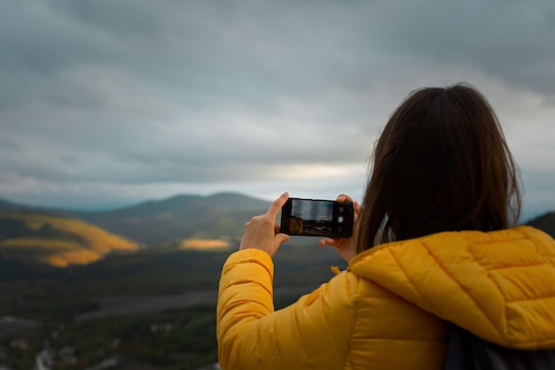 Photographe paysage d'automne une jeune femme touriste photographie un coucher de soleil dans les montagnes