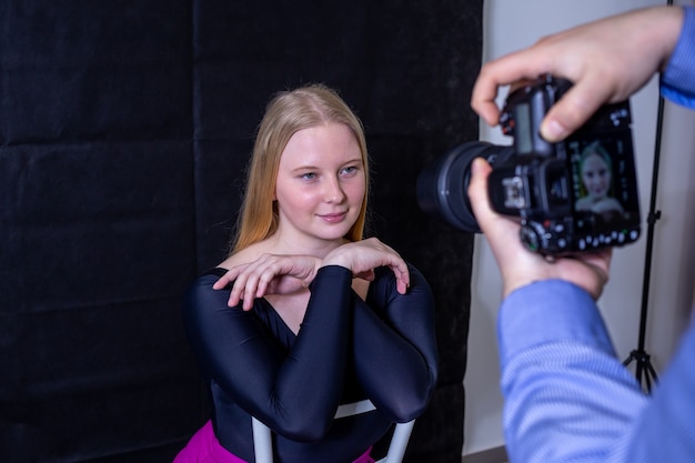 Photographe prenant une photo de jeune femme blonde aux yeux bleus sur fond noir