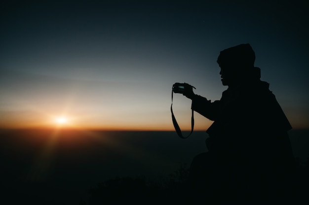 Photographe prenant des photos sur la vue de la montagne avec le lever du soleil silhouette.