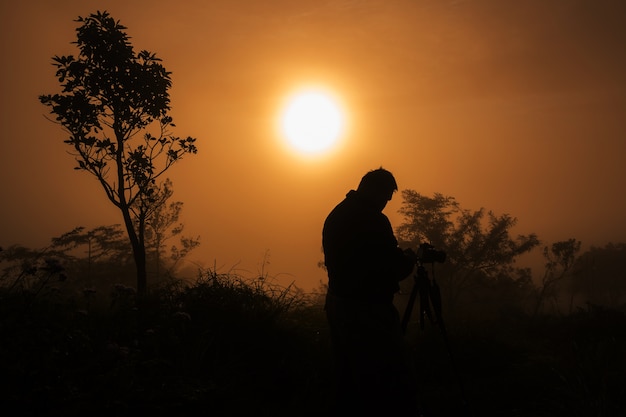 photographe prend des photos les premiers rayons du soleil levant sur la montagne. Paysage fogy rêveur