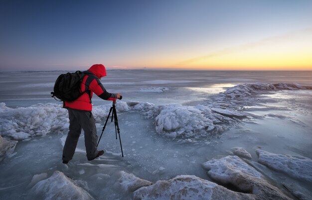 Photographe prendre des photos sur la rive du fleuve en hiver