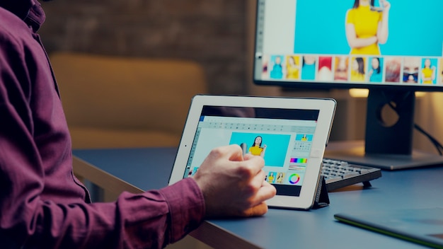 Photographe retouchant des détails sur une photo à l'aide d'une tablette et d'un stylo graphique.