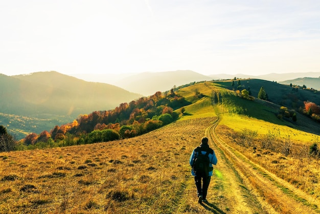 Le photographe sur la route au sol fait une photo du paysage d'automne