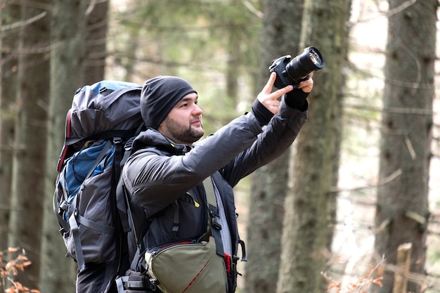 Photographe avec sac à dos de randonnée à prendre des photos de la nature avec un appareil photo numérique.