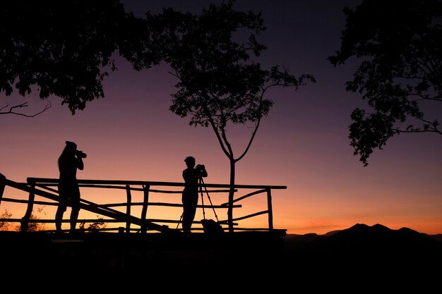 Photographe silhouette sur la montagne en prenant des photos de paysage avec coucher de soleil ou lever de soleil - photographe femme avec appareil photo