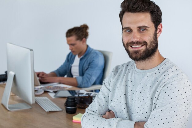 Photographe souriant debout avec les bras croisés en studio